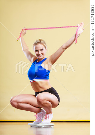 Joyful girl standing on bathroom scales 121718653