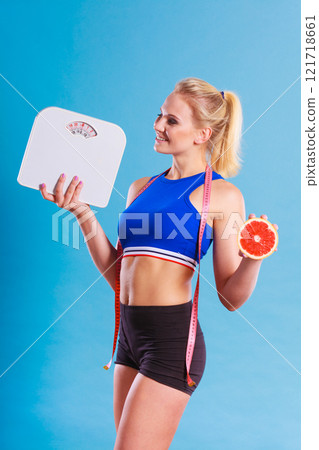 Fit woman holds weight scale grapefruit 121718661