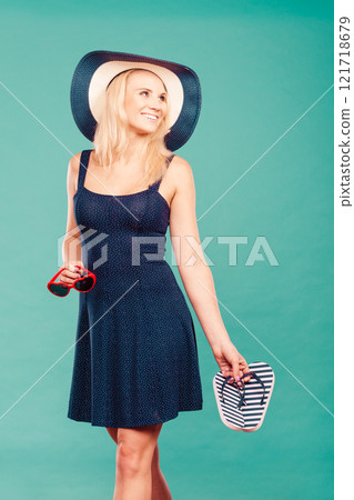 Woman wearing short dress holding flip flops and sunglasses Woman wearing short dress holding flip flops and sunglasses 121718679