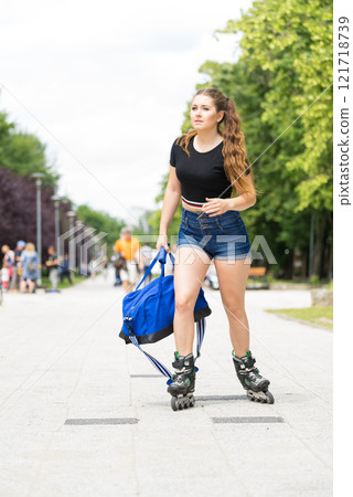 Young woman riding roller skates holding bag Young woman riding roller skates holding bag 121718739