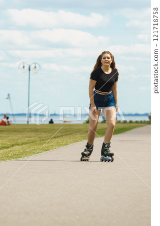 Young woman riding roller skates 121718758