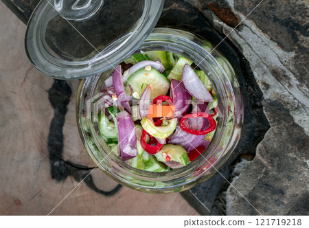 Top view of Homemade thai cucumber slices, chili slices and shallots relish slices and vinegar in a glass jar. Top view of Homemade thai cucumber slices, chili slices and shallots relish slices and vinegar in a glass jar. 121719218