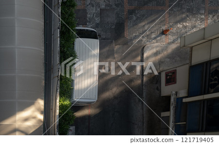 Top view of a white van parked next to a wall near a parking lot and morning light shining through. Top view of a white van parked next to a wall near a parking lot and morning light shining through. 121719405