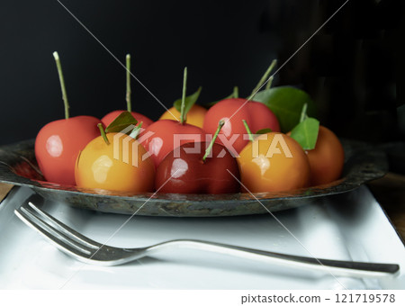 Deletable imitation fruits (Kanom look choup) has a sweet taste in small leaf shaped metal platter served with dessert fork on white tray. use it as your Wallpaper, Poster and Space for text, 121719578