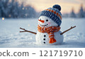 A happy snowman with a blue hat and orange scarf stands joyfully in a snowy field, capturing the essence of winter fun. 121719710