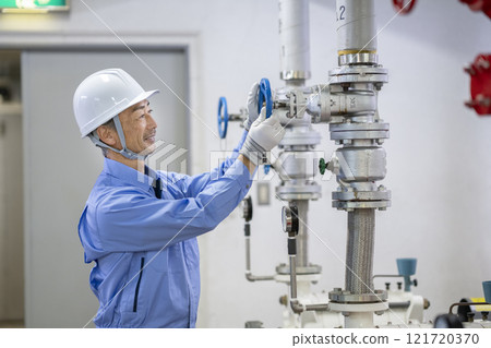Building maintenance staff image: Profile of a veteran worker inspecting water supply equipment 121720370