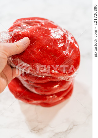 Four portions of the Classic Red Gingerbread Dough, each wrapped in plastic, are stacked and ready for refrigeration. This step allows the dough to rest and develop flavor before baking. Four portions of the Classic Red Gingerbread Dough, each wrapped in plastic, are stacked and ready for refrigeration. This step allows the dough to rest and develop flavor before baking. 121720890
