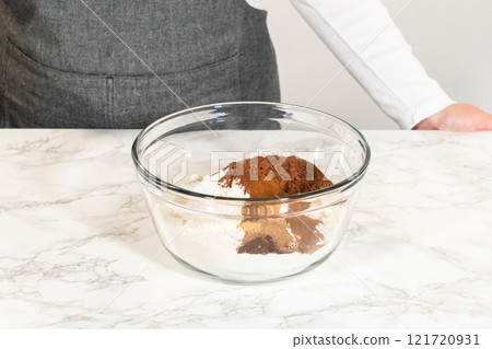 A bowl containing dry ingredients for Chocolate Gingerbread Cookie Dough, including cocoa powder, spices, and flour, ready to be mixed on a marble countertop. A bowl containing dry ingredients for Chocolate Gingerbread Cookie Dough, including cocoa powder, spices, and flour, ready to be mixed on a marble countertop. 121720931