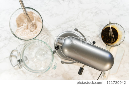 Overhead view of a mixing setup with flour, spices, and a stand mixer for Spiced Gingerbread Cookie Dough Perfect for Baking. Bowls of dry and wet ingredients are ready for blending. 121720942