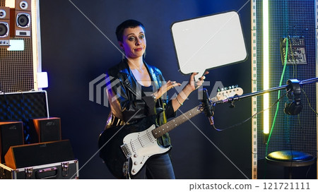 Female rock star performer showing the empty cardboard speech bubble, presenting her rebellious grunge attitude as an artist. Woman musician does a commercial ad with billboard. Camera A. Female rock star performer showing the empty cardboard speech bubble, presenting her rebellious grunge attitude as an artist. Woman musician does a commercial ad with billboard. Camera A. 121721111
