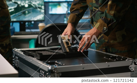 Operatives conducing special operation, loading weapons, preparing to attack enemy forces. Close up of army soldier in command center packing guns for assault mission, camera A 121721142