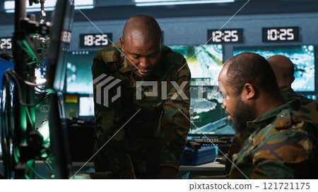 Military agents in war room look at intel folder files on enemy battle formation. Intelligence agency professionals read mission case file to collect data on opponents strategy, camera A Military agents in war room look at intel folder files on enemy battle formation. Intelligence agency professionals read mission case file to collect data on opponents strategy, camera A 121721175