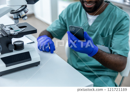 Medical man working in lab using smartphone and microscope for analysis and research 121721189
