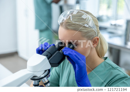 Female doctor in clinic using modern microscope and equipment for concentrated study 121721194