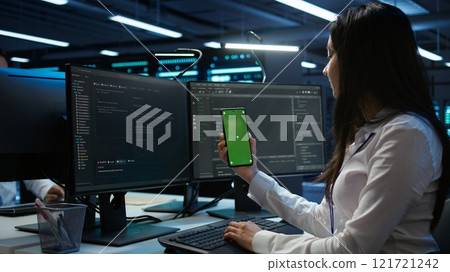 Worker overseeing data center using green screen mobile phone, ensuring system can handle networking tasks. IT expert in server room tracking network traffic with empty copy space smartphone, camera B 121721242