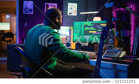 Musical producer prepares to record tunes on acoustic instrument, working in personal home studio to record soundtrack. Sound composer recording guitar music, editing with mixing console. Camera B. Musical producer prepares to record tunes on acoustic instrument, working in personal home studio to record soundtrack. Sound composer recording guitar music, editing with mixing console. Camera B. 121721251