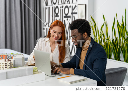 Two colleagues discussing a new project in the office and looking excited Two colleagues discussing a new project in the office and looking excited 121721278