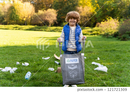 Male child cleaning trash in park participating in social project to protect nature and reduce waste 121721309