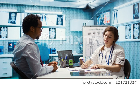 Physician writing a prescription with the recommended treatment and supplements for wellness, giving instructions and medical advice to patient. Prescribe medication on insurance. Camera B. 121721324