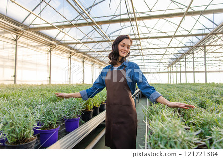 Young female greenhouse worker looking happy and smiling 121721384
