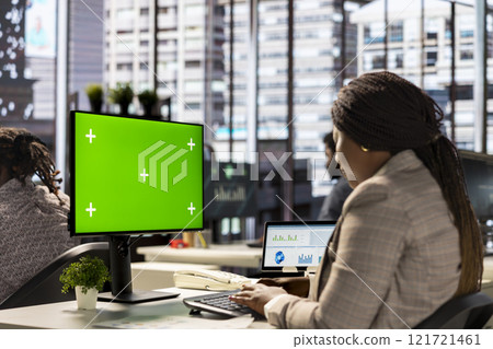 Female executive seated at her workstation with isolated copy space multitasking, analyzing financial reports to support strategic business goals and decision making processes. Female executive seated at her workstation with isolated copy space multitasking, analyzing financial reports to support strategic business goals and decision making processes. 121721461