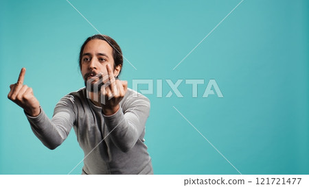 Irked man fighting with friend, doing middle finger sign gesturing, isolated over studio background. Outraged person arguing during conversation, doing obscene hand gestures, camera B 121721477
