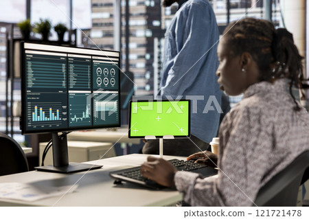 Female executive seated at her workstation with isolated copy space multitasking, analyzing financial reports to support strategic business goals and decision making processes. 121721478