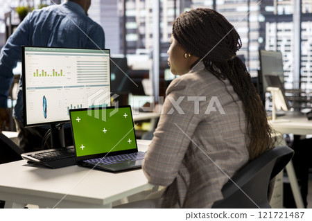 Woman at her desk working on data analysis next to mockup display, engaged in business tasks and budget management to drive effective corporate strategy. Analyst reads reports numbers. Woman at her desk working on data analysis next to mockup display, engaged in business tasks and budget management to drive effective corporate strategy. Analyst reads reports numbers. 121721487