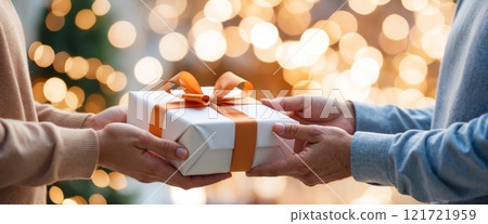 A close-up of hands giving a beautifully wrapped gift to another person. The scene conveys warmth, care, and symbolizes gratitude. 121721959