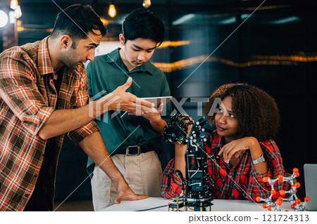 In a classroom setting students and teacher engage in learning on a robotic arm. Fostering innovation teamwork and problem-solving in education. Robot hand. Innovation and technology concept 121724313