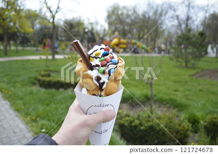 hand with sweet waffles with ice cream and candies 121724678