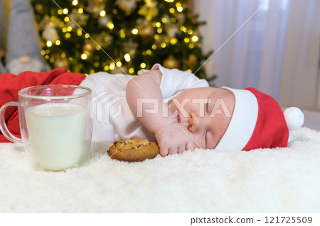 Two-Month-Old Baby in a Christmas Outfit with Milk and Cookies. Selective Focus Two-Month-Old Baby in a Christmas Outfit with Milk and Cookies. Selective Focus 121725509