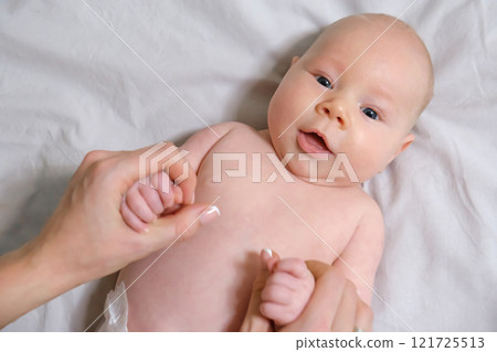 Joyful Two-Month-Old Baby Boy Holding Mom's Hands on a Light Background. Selective Focus Joyful Two-Month-Old Baby Boy Holding Mom's Hands on a Light Background. Selective Focus 121725513