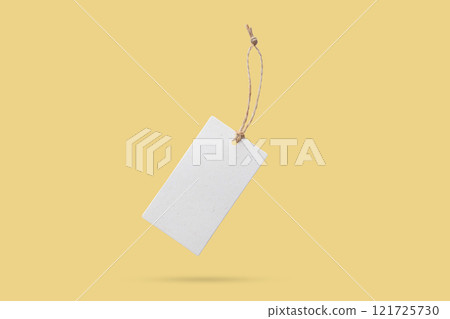 Blank price tag tied with string float on yellow background 121725730