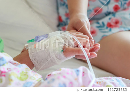 Mother holding child hand with saline IV solution in hospital Mother holding child hand with saline IV solution in hospital 121725883