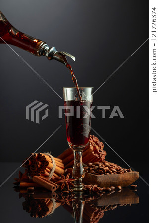 Coffee liquor is poured from a bottle into a glass. 121726374