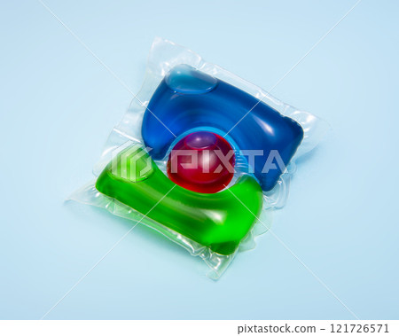 Liquid powder in gel capsule for washing multicolor on blue background Liquid powder in gel capsule for washing multicolor on blue background 121726571