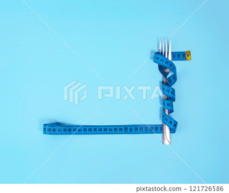 Metal fork and blue tape measure on blue background Metal fork and blue tape measure on blue background 121726586