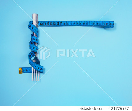 Metal fork and blue tape measure on blue background Metal fork and blue tape measure on blue background 121726587