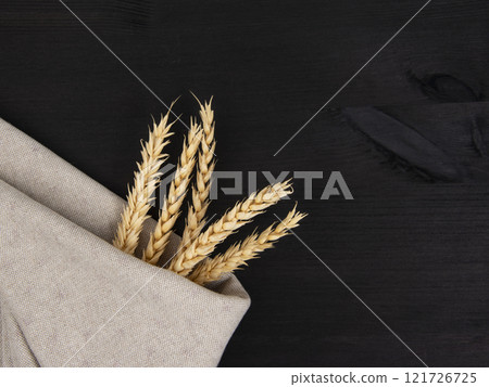 Natural wheat on craft fabric concept on dark black background with copy space Natural wheat on craft fabric concept on dark black background with copy space 121726725