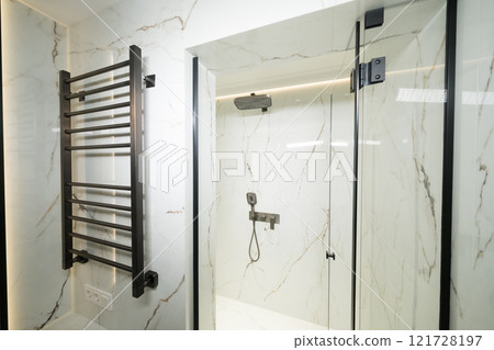 Modern black radiator on white marble wall in bathroom. New bathroom with granite white tiles Modern black radiator on white marble wall in bathroom. New bathroom with granite white tiles 121728197