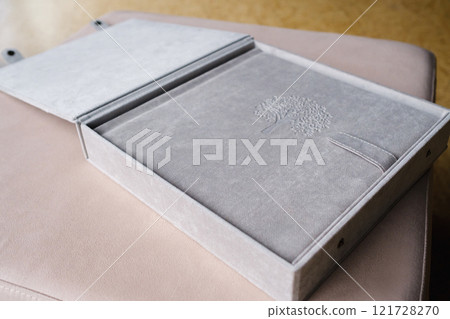 A photo book in a grey cloth cover lies on the box. the concept of creating books and albums from photographs. professional photographer and printing services A photo book in a grey cloth cover lies on the box. the concept of creating books and albums from photographs. professional photographer and printing services 121728270