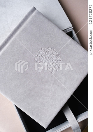 A photo book in a grey cloth cover lies on the box. the concept of creating books and albums from photographs. professional photographer and printing services A photo book in a grey cloth cover lies on the box. the concept of creating books and albums from photographs. professional photographer and printing services 121728272