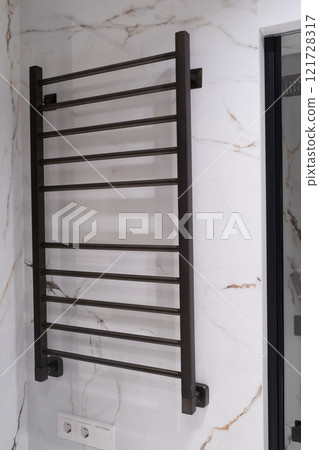 Modern black radiator on white marble wall in bathroom. New bathroom with granite white tiles 121728317