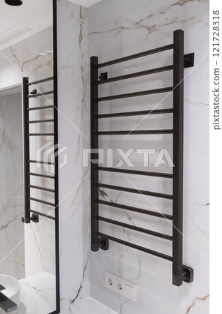 Modern black radiator on white marble wall in bathroom. New bathroom with granite white tiles Modern black radiator on white marble wall in bathroom. New bathroom with granite white tiles 121728318