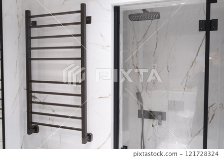 Modern black radiator on white marble wall in bathroom. New bathroom with granite white tiles 121728324
