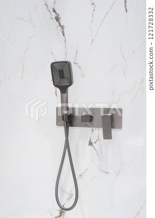 Luxury chrome faucet and shower in shower stall with white marble walls. Modern luxury shower cubicle 121728332