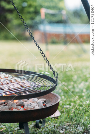 Enjoying eco friendly grilling with low waste cooking methods over a natural fire pit in a tranquil outdoor setting during a sunny afternoon Enjoying eco friendly grilling with low waste cooking methods over a natural fire pit in a tranquil outdoor setting during a sunny afternoon 121728404