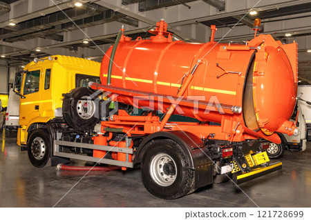 Bright orange industrial truck poses in a modern warehouse during a busy workday Bright orange industrial truck poses in a modern warehouse during a busy workday 121728699