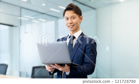 A smiling businessman with a laptop 121728780